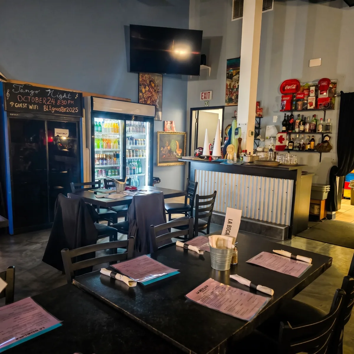 La Boca Loca dining room with tables set with menus, a chalkboard and a drinks fridge